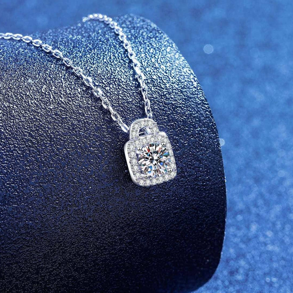 Platinum-plated moissanite lock pendant necklace on blue textured background