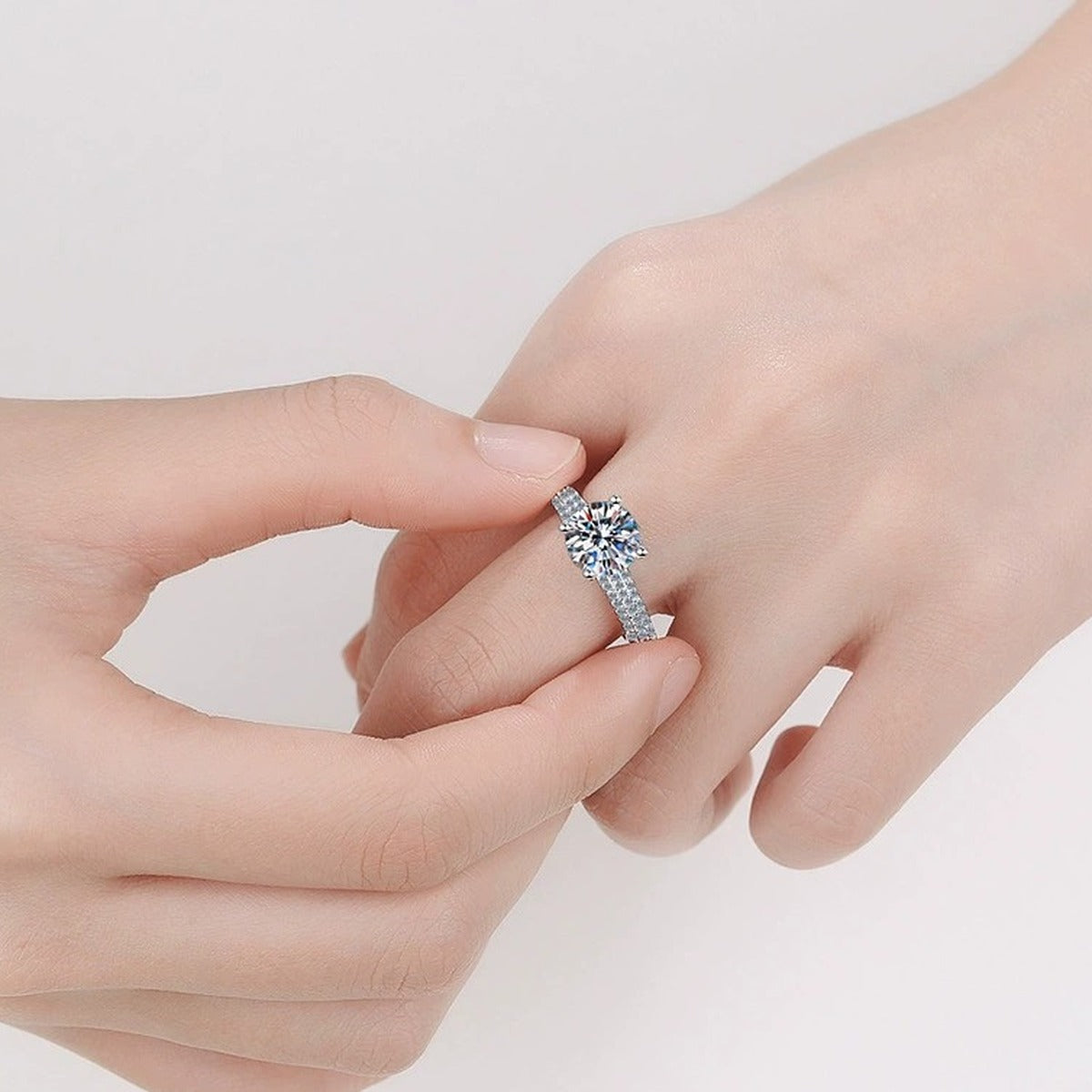 Round Moissanite Side Stone Engagement Ring with CZ worn on hand to show scale, band width, and ring profile