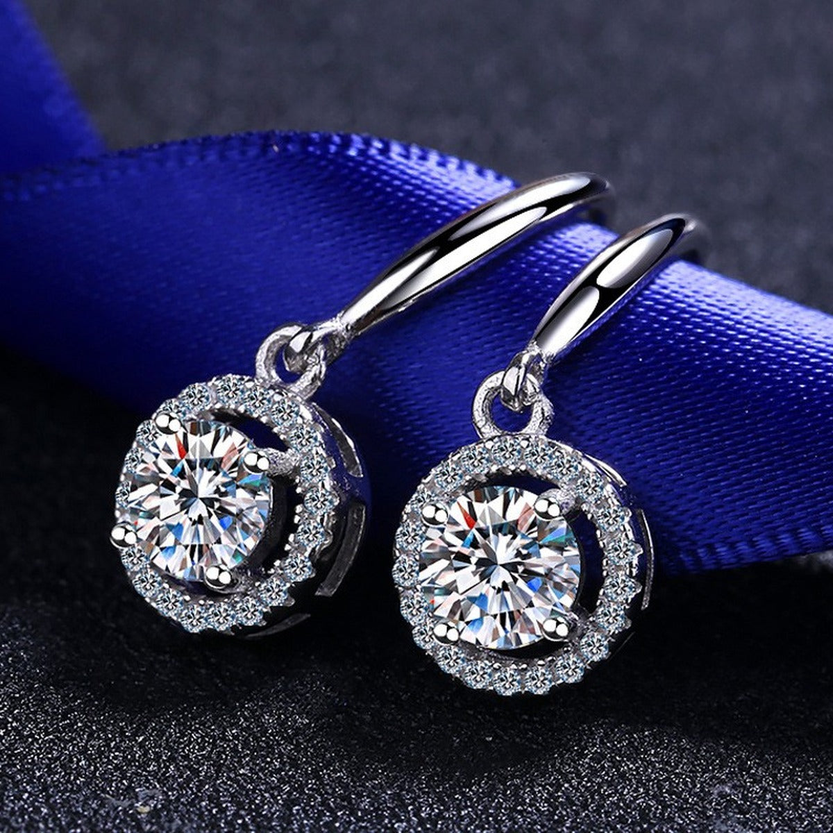 Round Halo Moissanite Hook Dangle Earrings with CZ in Rhodium-Plated S925 Sterling Silver on blue-green fabric showing side profile and stone setting