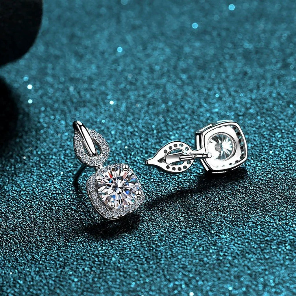 Cushion Halo Moissanite Stud Drop Earrings with CZ in Rhodium-Plated S925 Sterling Silver on blue-green fabric showing front detail