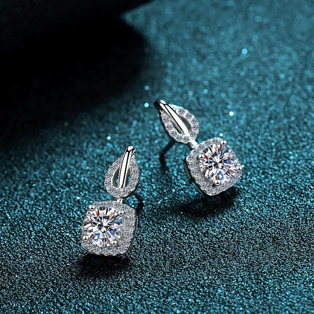 Cushion Halo Moissanite Stud Drop Earrings with CZ in Rhodium-Plated S925 Sterling Silver on blue-green fabric showing angled setting view