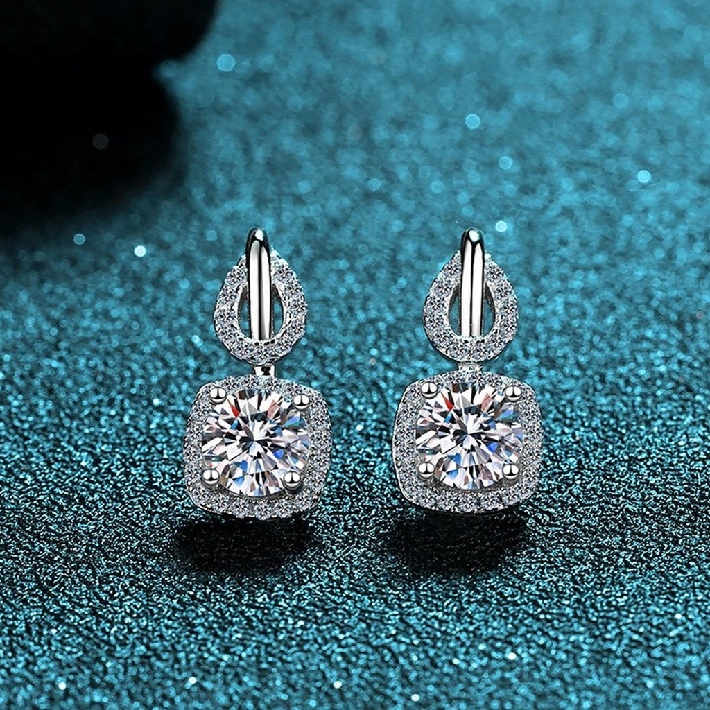 Cushion Halo Moissanite Stud Drop Earrings with CZ in Rhodium-Plated S925 Sterling Silver on blue-green fabric showing side profile and stone setting