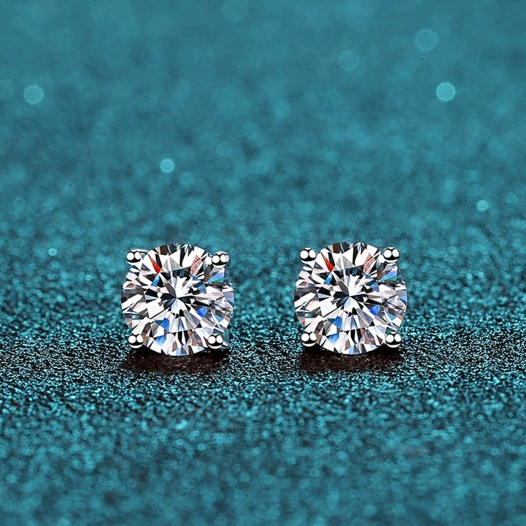 Classic Round Moissanite Stud Earrings in Rhodium-Plated S925 Sterling Silver on blue-green fabric showing side profile and stone setting