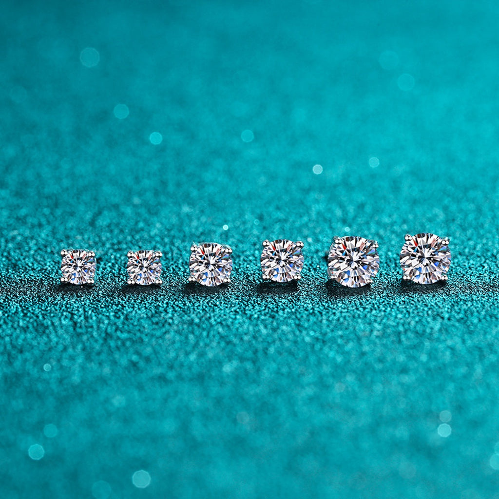 Classic Round Moissanite Stud Earrings in Rhodium-Plated S925 Sterling Silver on blue-green fabric showing full pair comparison