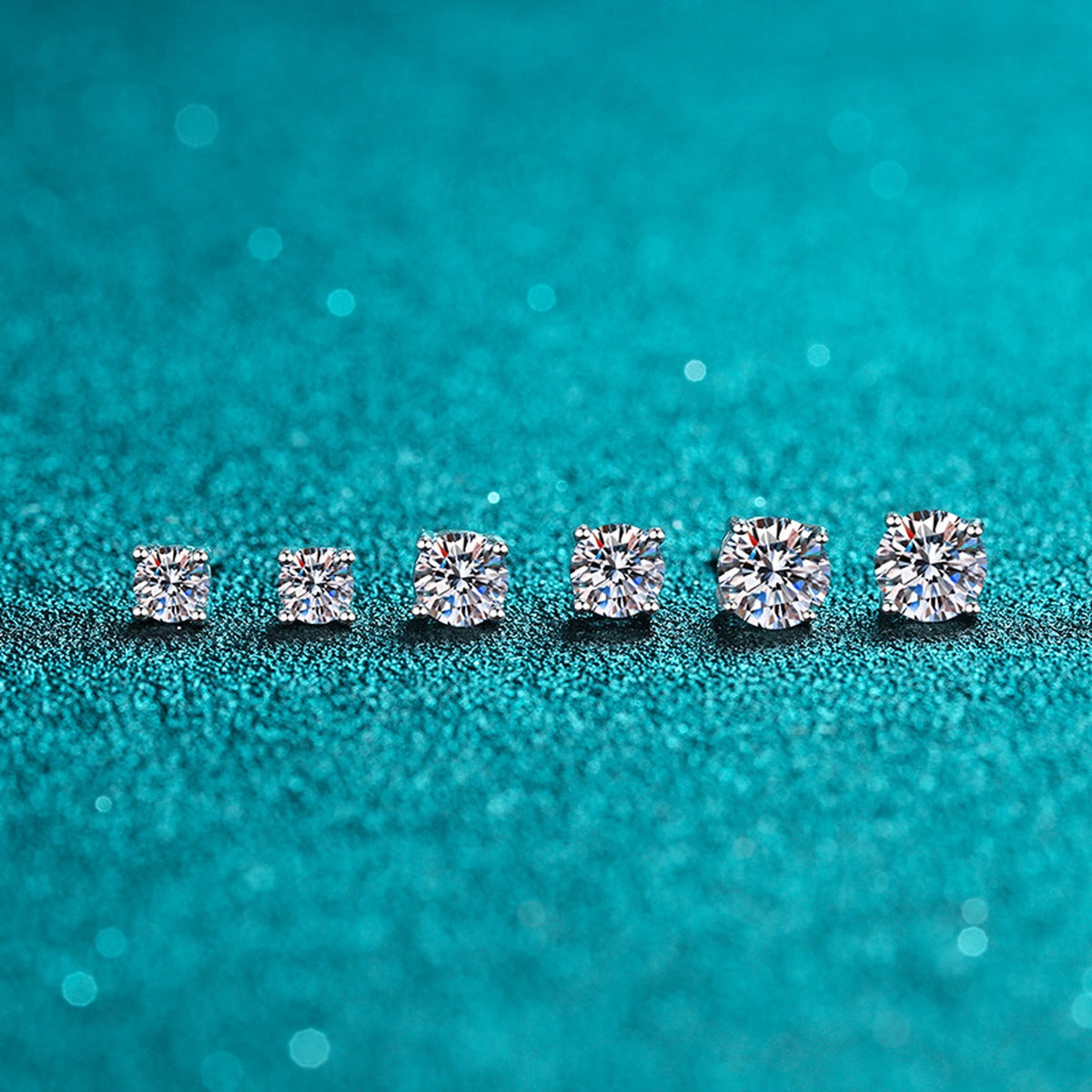 Classic Round Moissanite Stud Earrings in Rhodium-Plated S925 Sterling Silver on blue-green fabric showing full pair comparison