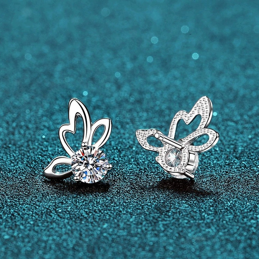 Butterfly Moissanite Stud Earrings in Rhodium-Plated S925 Sterling Silver on blue-green fabric showing side profile and stone setting
