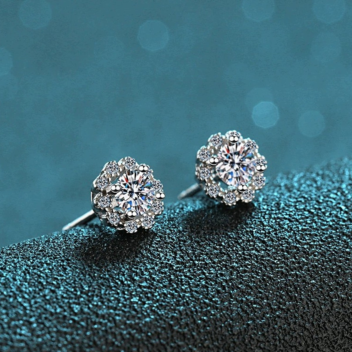 Floral Halo Moissanite Stud Earrings with CZ in Rhodium-Plated S925 Sterling Silver on blue-green fabric showing angled setting view