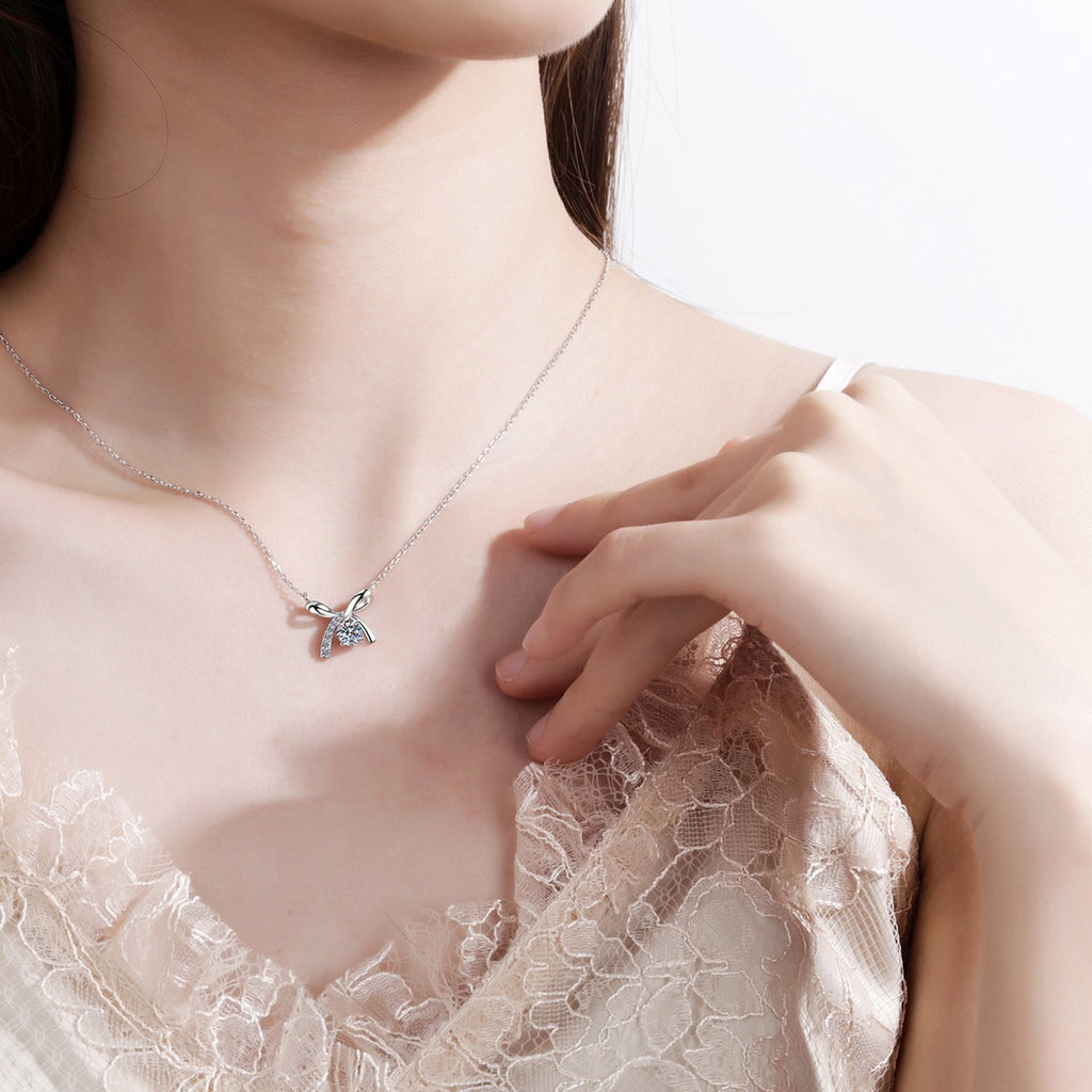 Ribbon Bow Moissanite Pendant Necklace with CZ in Rhodium-Plated S925 sterling silver worn on neckline by model showing scale and adjustable chain styling