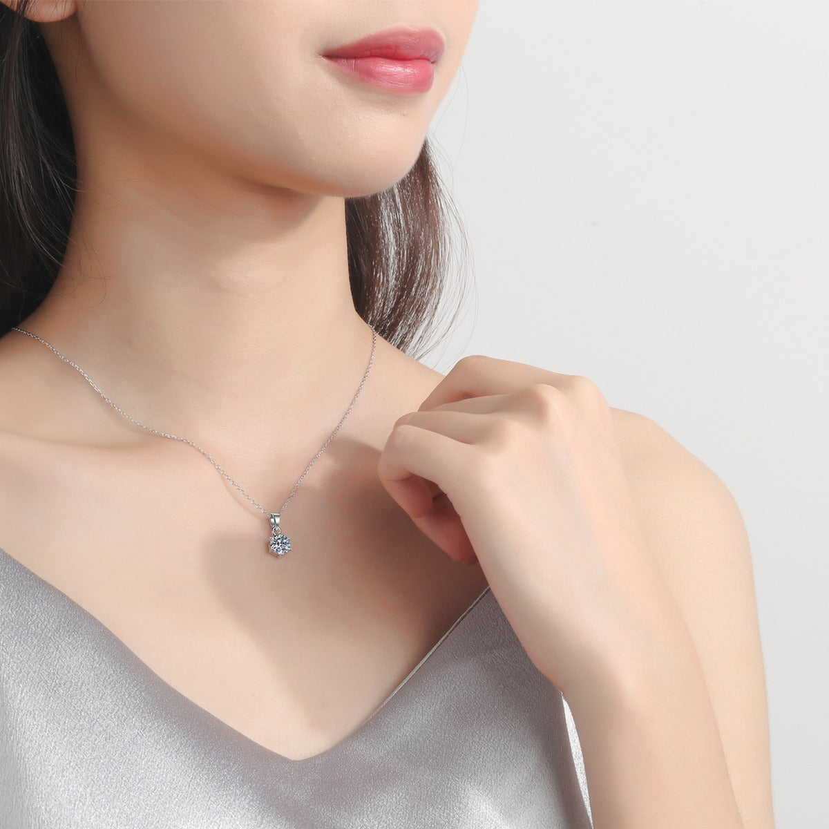 Solitaire Moissanite Pendant Necklace in Rhodium-Plated S925 sterling silver worn on neckline by model showing scale and adjustable chain styling