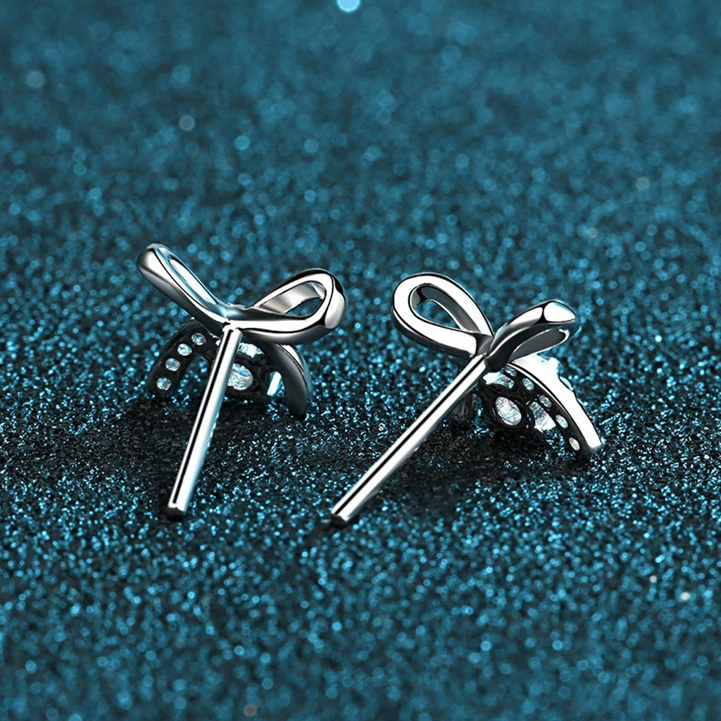 Bow Moissanite Stud Earrings with CZ in Rhodium-Plated S925 Sterling Silver on blue-green fabric showing front detail