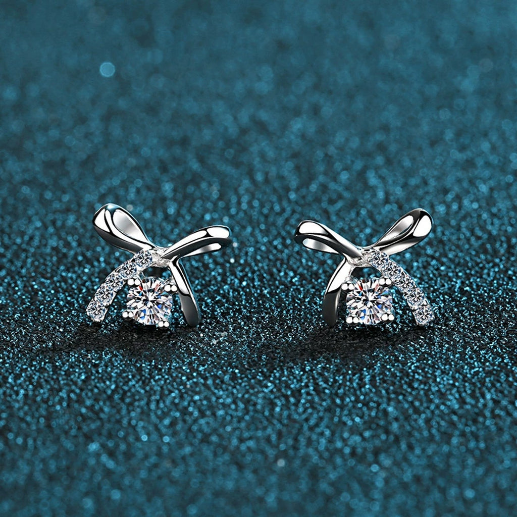 Bow Moissanite Stud Earrings with CZ in Rhodium-Plated S925 Sterling Silver on blue-green fabric showing side profile and stone setting