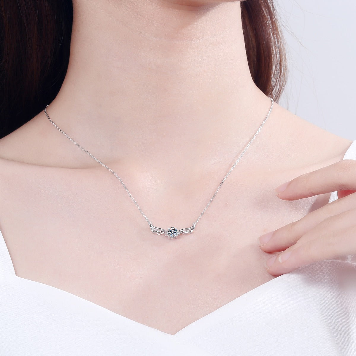 Angel Wing Moissanite Pendant Necklace in Rhodium-Plated S925 sterling silver worn on neckline by model showing scale and adjustable chain styling
