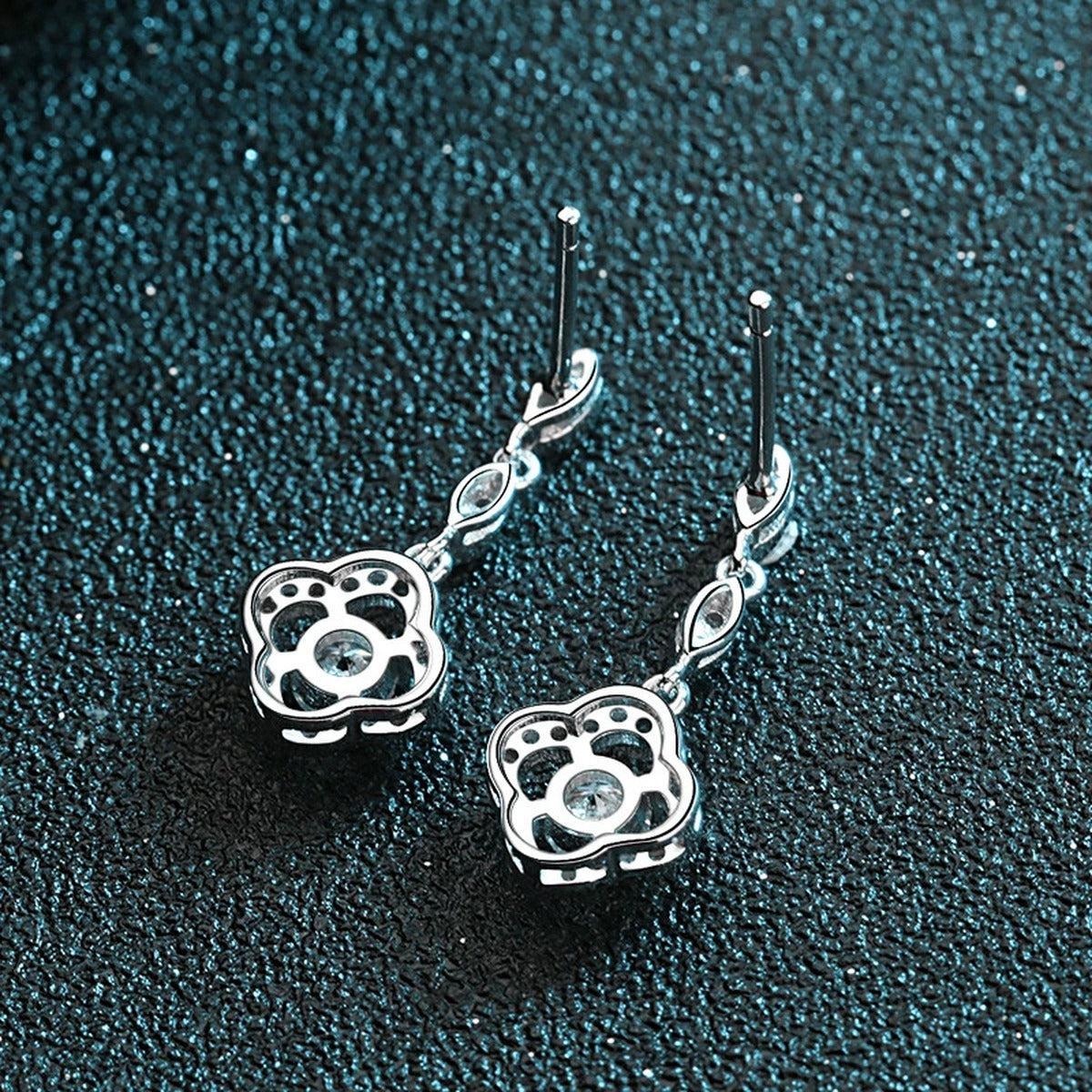 Clover Moissanite Stud Dangle Earrings with CZ in Rhodium-Plated S925 Sterling Silver on blue-green fabric showing side profile and stone setting