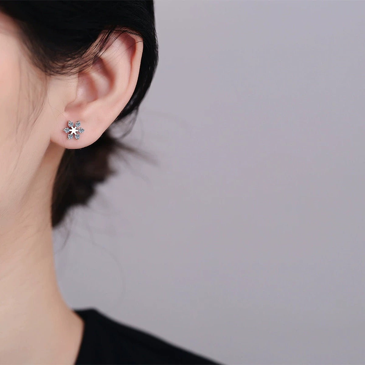 Snowflake Moissanite Stud Earrings in Rhodium-Plated S925 sterling silver worn on ear by model showing scale, placement, and stud earrings styling