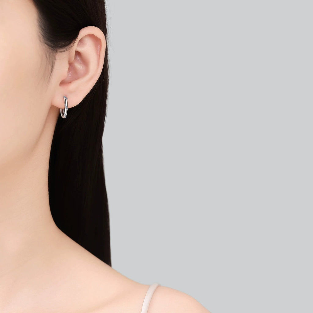 Twisted Pave Moissanite Hoop Earrings in Rhodium-Plated S925 sterling silver worn on ear by model showing scale, placement, and hoop earrings styling
