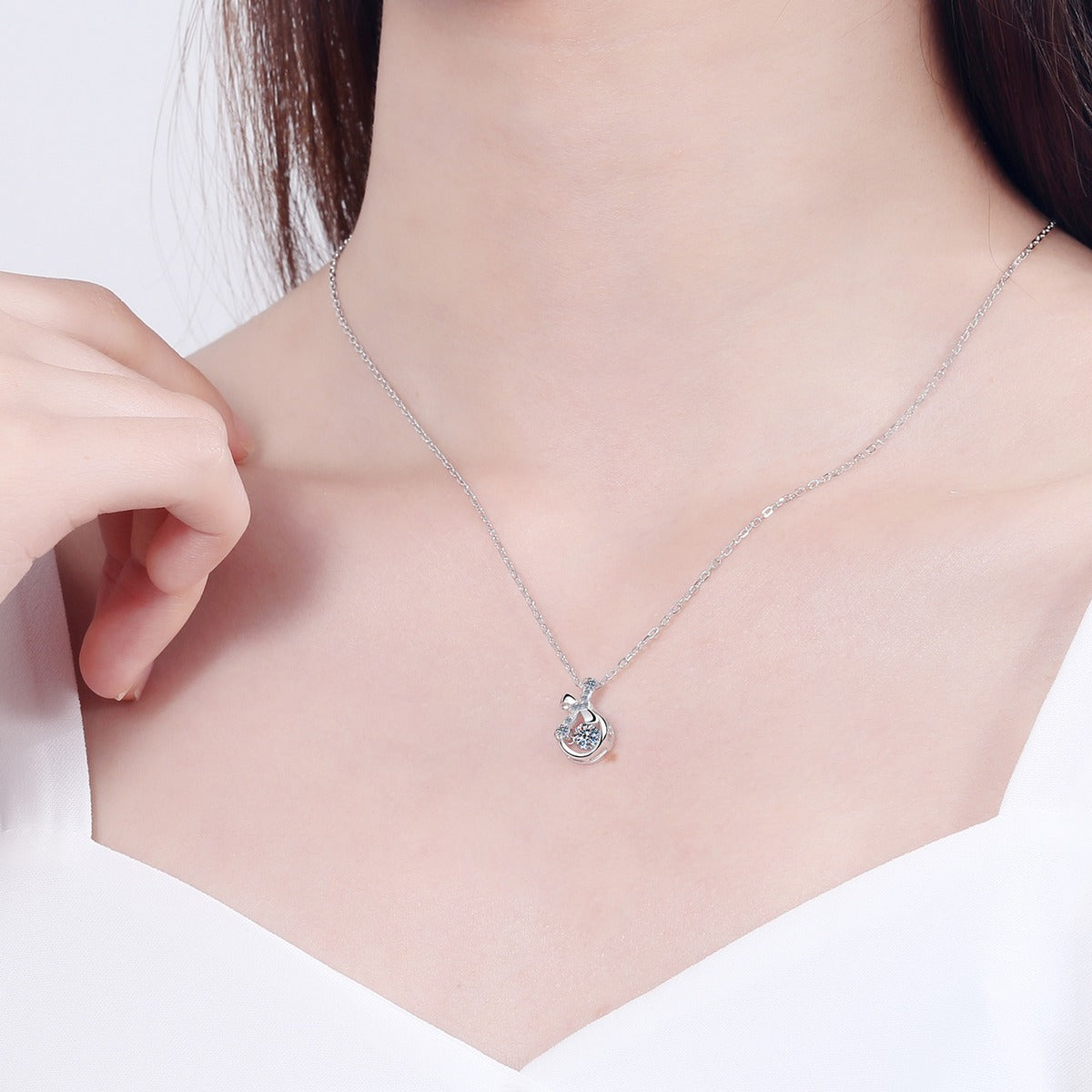 Ribbon Bow Moissanite Pendant Necklace with CZ in Rhodium-Plated S925 sterling silver worn on neckline by model showing scale and adjustable chain styling