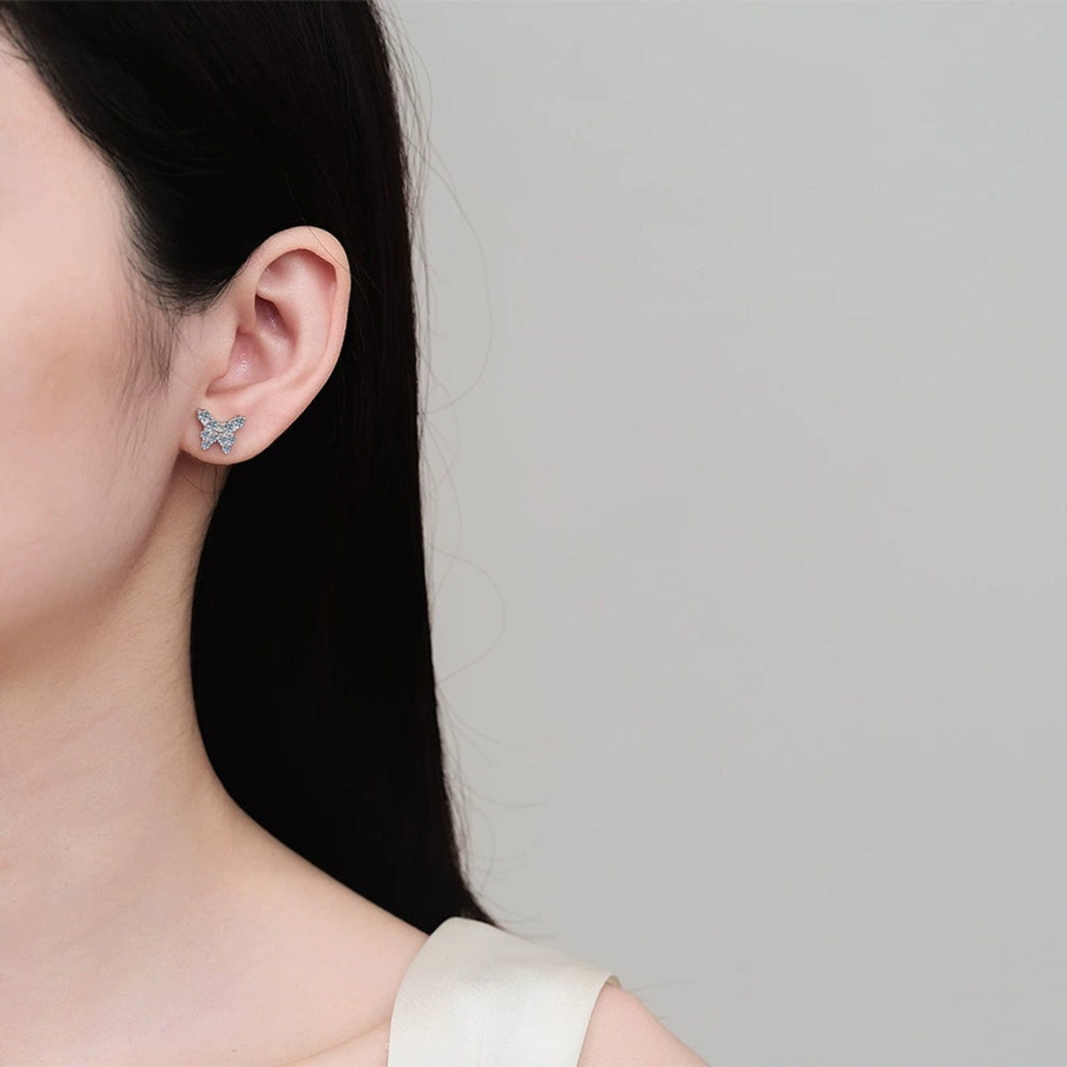 Butterfly Moissanite Stud Earrings in Rhodium-Plated S925 sterling silver worn on ear by model showing scale, placement, and stud earrings styling