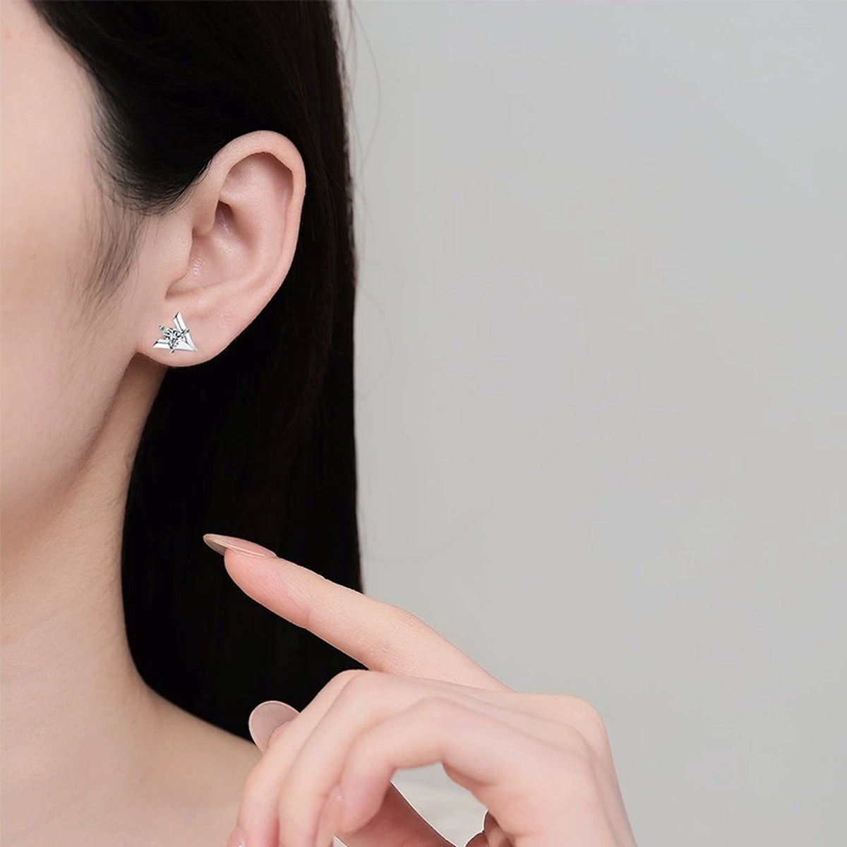 Trillion Cut Moissanite Stud Earrings in Rhodium-Plated S925 sterling silver worn on ear by model showing scale, placement, and stud earrings styling