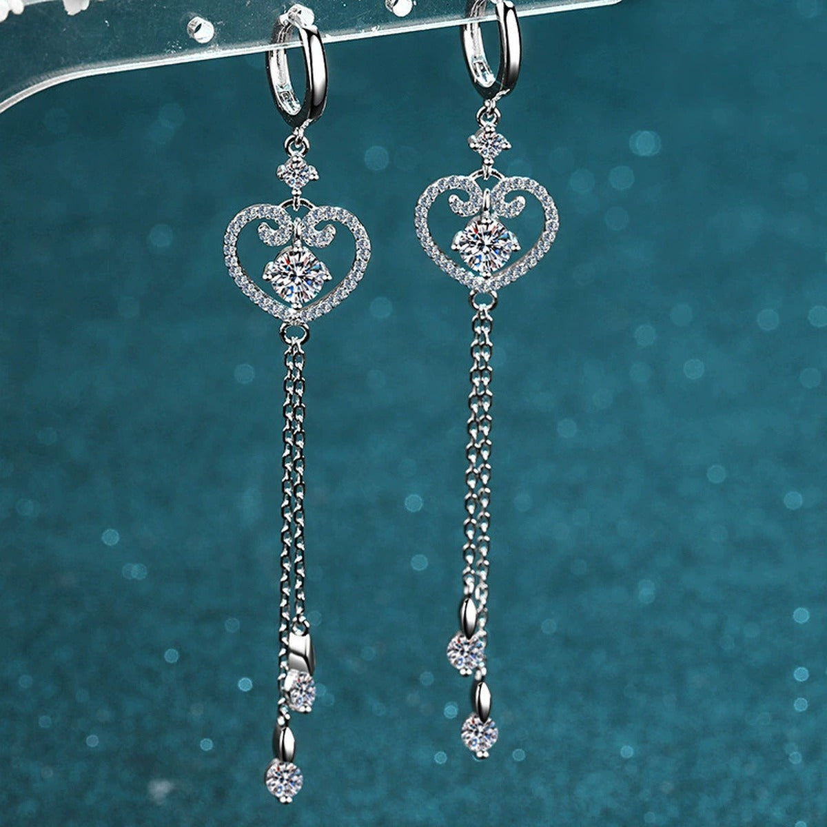 Heart Moissanite Hoop Dangle Earrings with CZ in Rhodium-Plated S925 Sterling Silver on blue-green fabric showing front detail