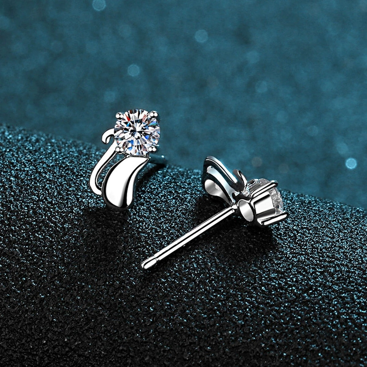 Cat Moissanite Stud Earrings in Rhodium-Plated S925 Sterling Silver on blue-green fabric showing front detail