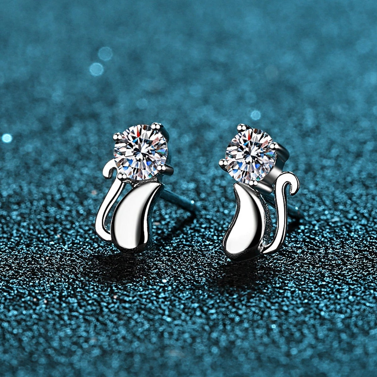 Cat Moissanite Stud Earrings in Rhodium-Plated S925 Sterling Silver on blue-green fabric showing side profile and stone setting