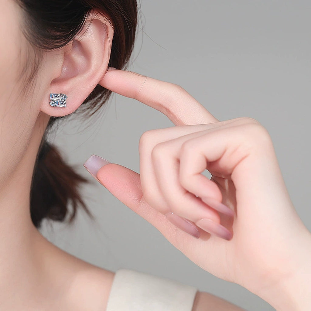 Emerald and Round Moissanite Stud Earrings in Rhodium-Plated S925 sterling silver worn on ear by model showing scale, placement, and stud earrings styling