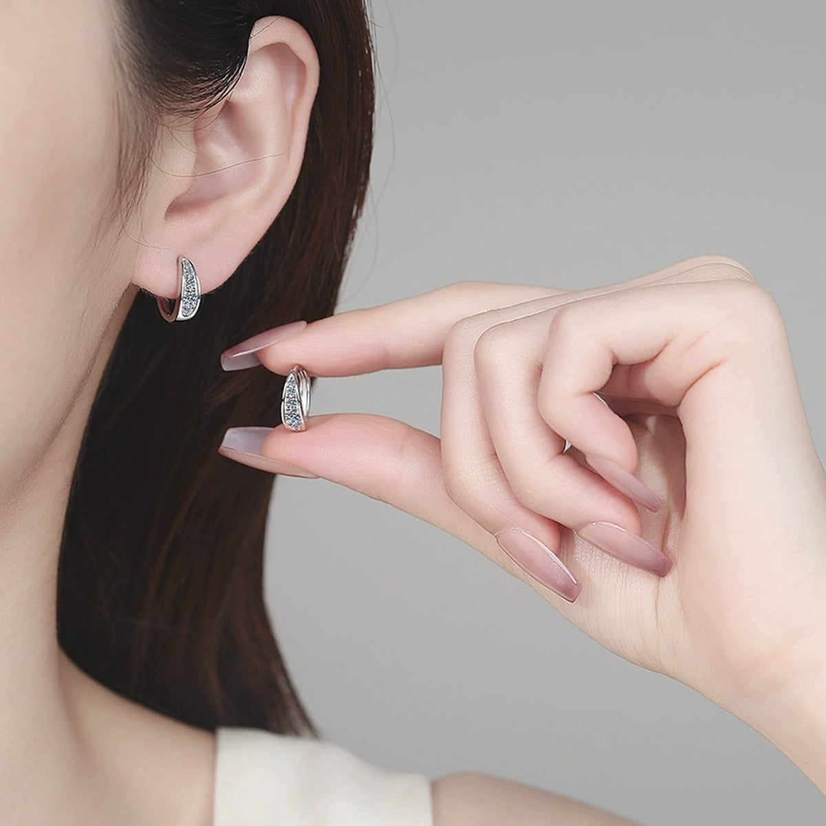 Pave Moissanite Huggie Hoop Earrings in Rhodium-Plated S925 sterling silver worn on ear by model showing scale, placement, and huggie hoop earrings styling