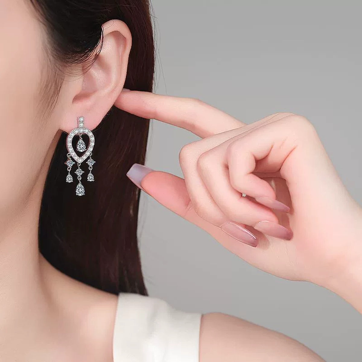 Pear and Round Moissanite Stud Chandelier Earrings in Rhodium-Plated S925 sterling silver worn on ear by model showing scale, placement, and stud dangle earrings styling