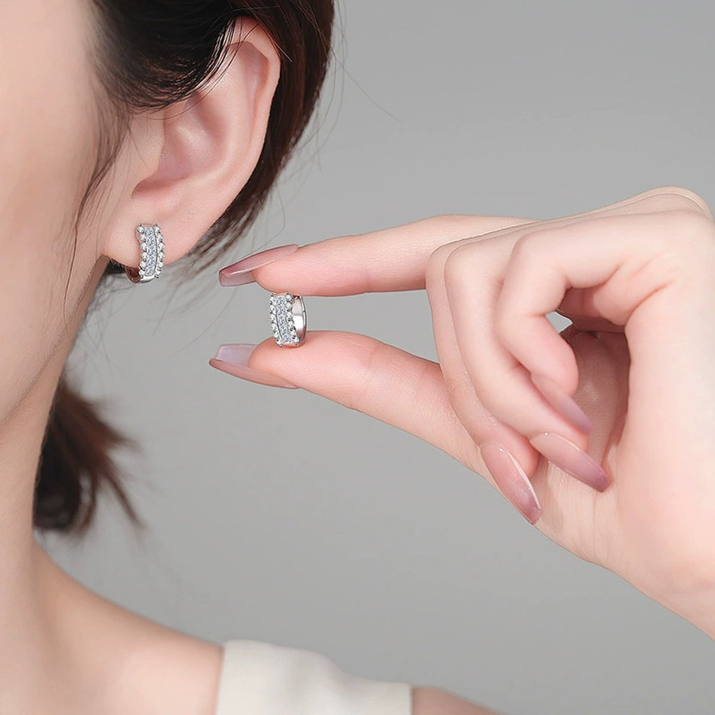 Round and Princess Cut Moissanite Huggie Hoop Earrings in Rhodium-Plated S925 sterling silver worn on ear by model showing scale, placement, and huggie hoop earrings styling