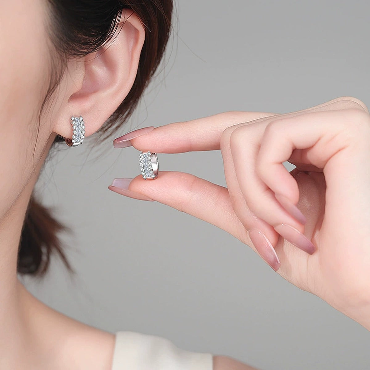 Round and Princess Cut Moissanite Huggie Hoop Earrings in Rhodium-Plated S925 sterling silver worn on ear by model showing scale, placement, and huggie hoop earrings styling