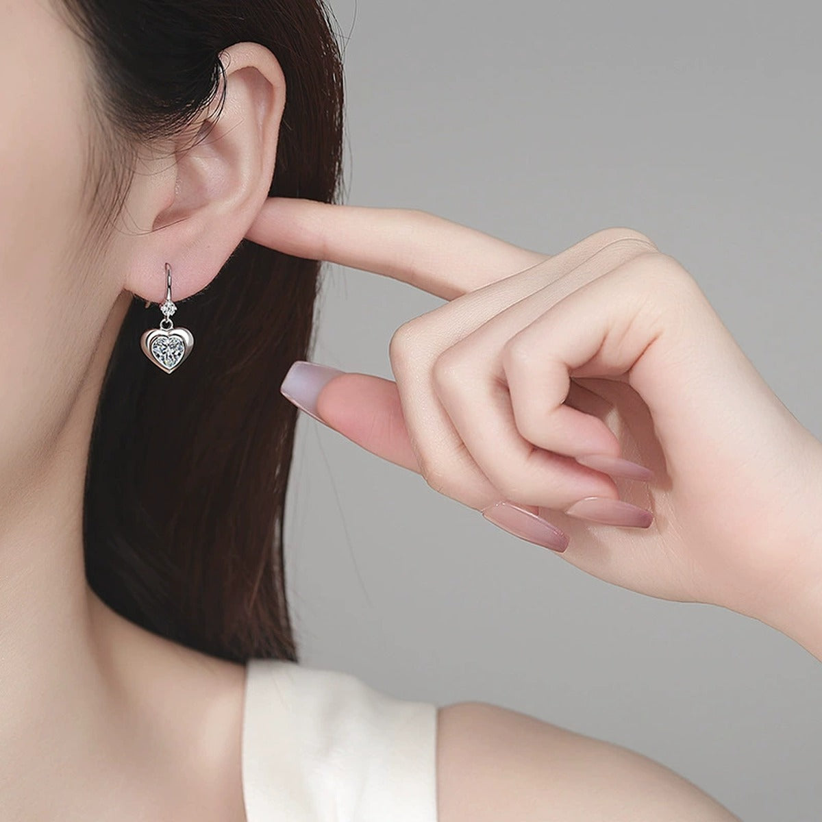 Heart Moissanite Hook Dangle Earrings in Rhodium-Plated S925 sterling silver worn on ear by model showing scale, placement, and hook dangle earrings styling