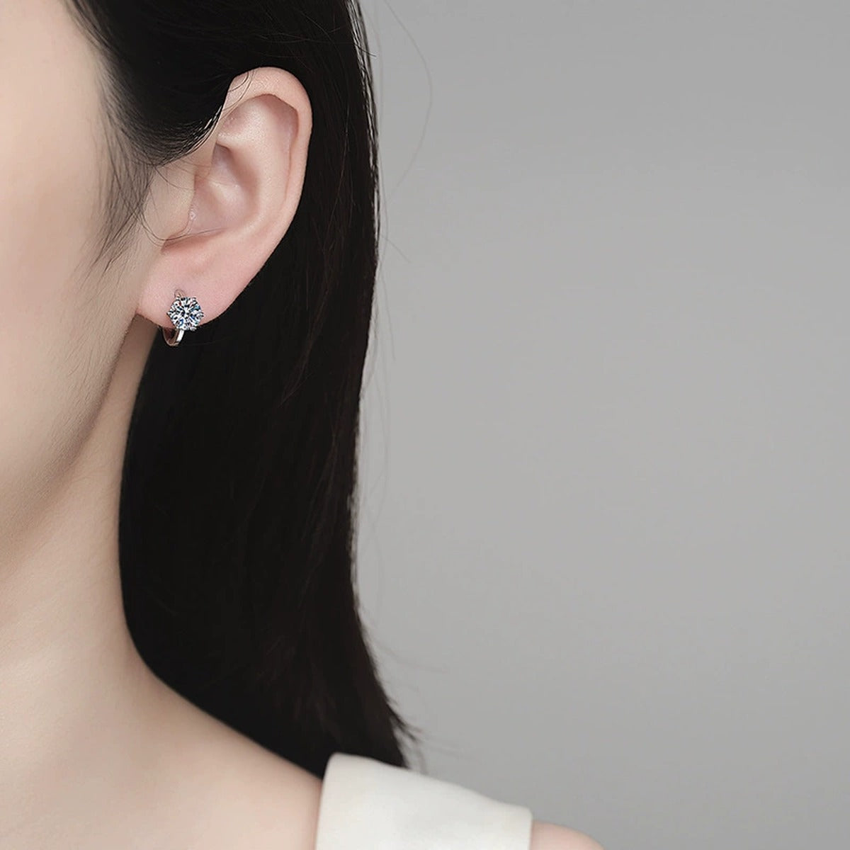 Round Moissanite Huggie Hoop Earrings in Rhodium-Plated S925 sterling silver worn on ear by model showing scale, placement, and huggie hoop earrings styling