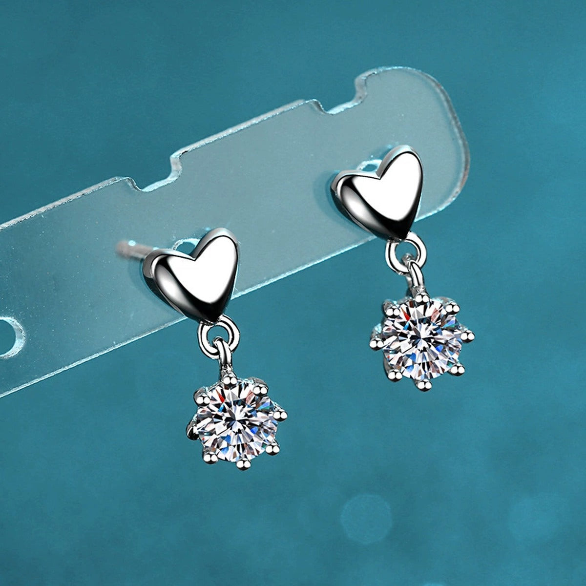 Heart Moissanite Stud Dangle Earrings in Rhodium-Plated S925 Sterling Silver on blue-green fabric showing front detail