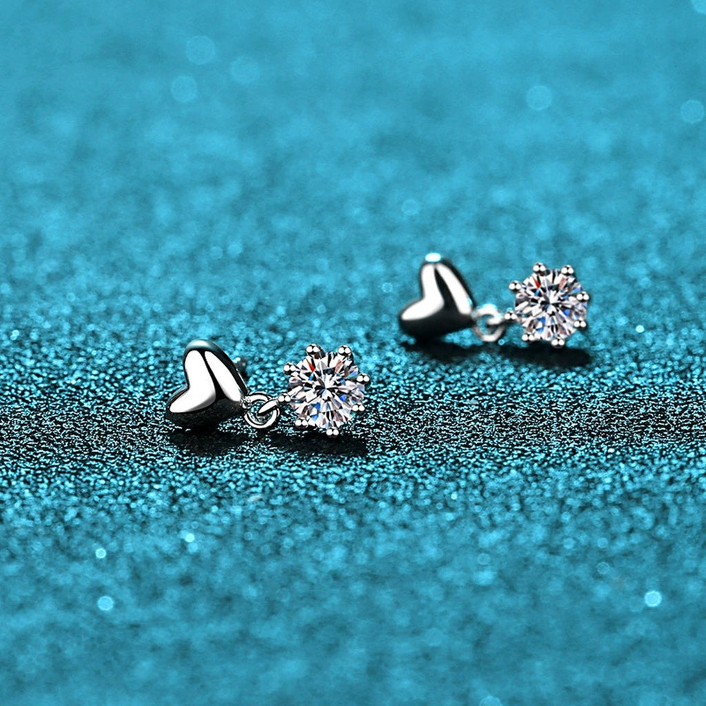 Heart Moissanite Stud Dangle Earrings in Rhodium-Plated S925 Sterling Silver on blue-green fabric showing side profile and stone setting
