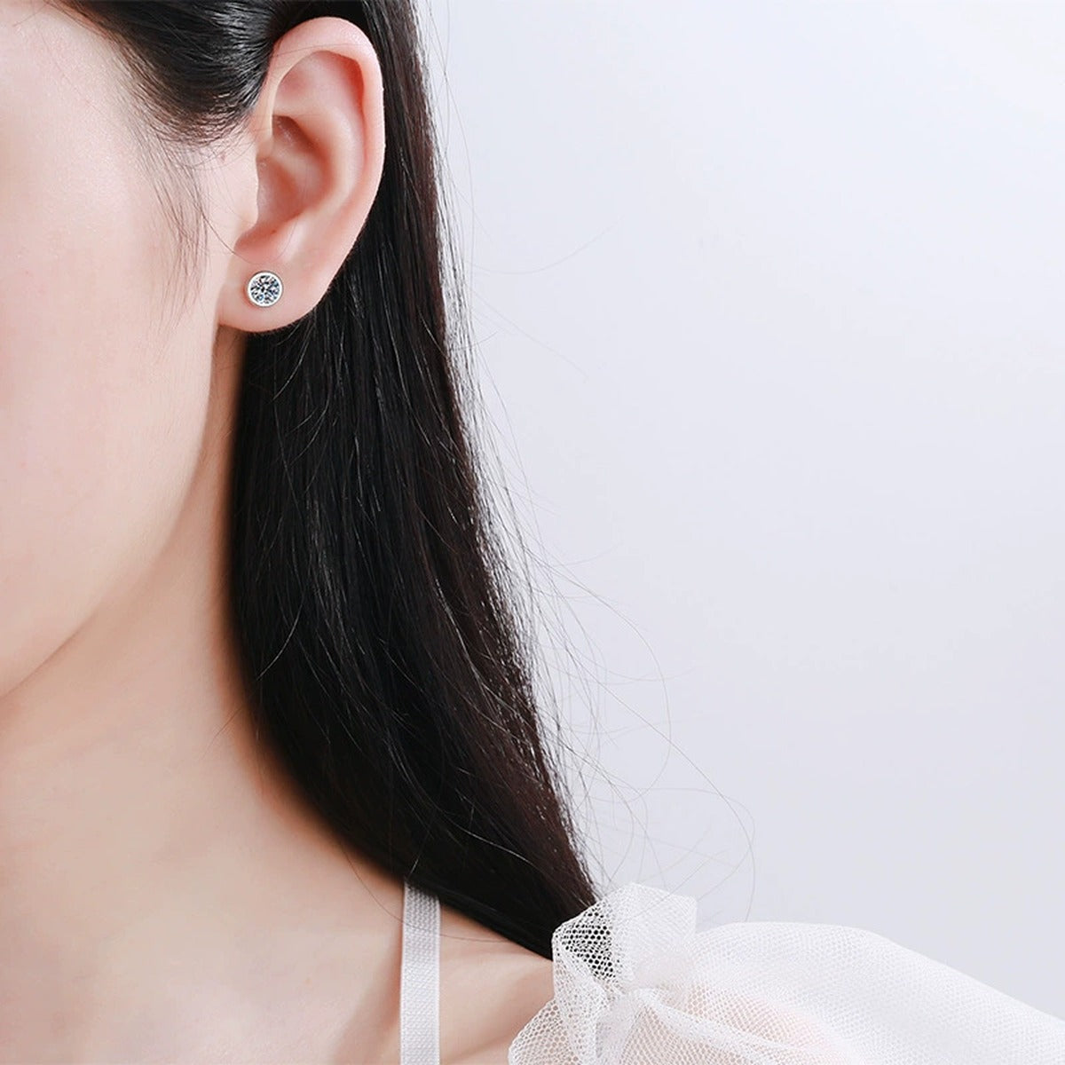Bezel Round Moissanite Stud Earrings in Rhodium-Plated S925 Sterling Silver worn on ear by model to show scale, drop length, and everyday styling
