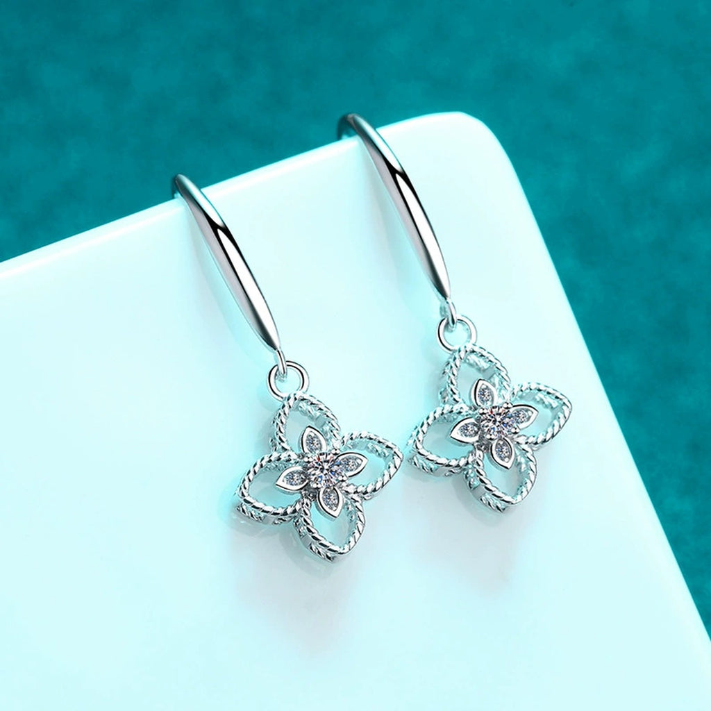 Floral Moissanite Hook Dangle Earrings in Rhodium-Plated S925 Sterling Silver on blue-green fabric showing angled setting view