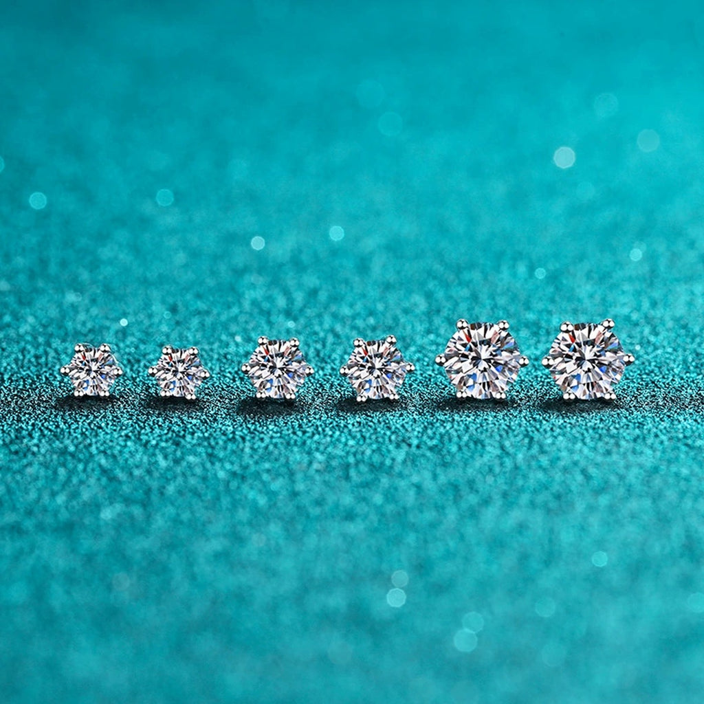 Classic Round Moissanite Stud Earrings in Rhodium-Plated S925 Sterling Silver on blue-green fabric showing side profile and stone setting