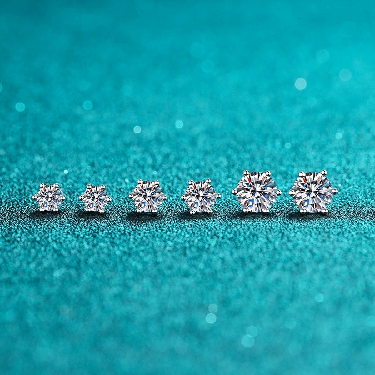 Classic Round Moissanite Stud Earrings in Rhodium-Plated S925 Sterling Silver on blue-green fabric showing side profile and stone setting