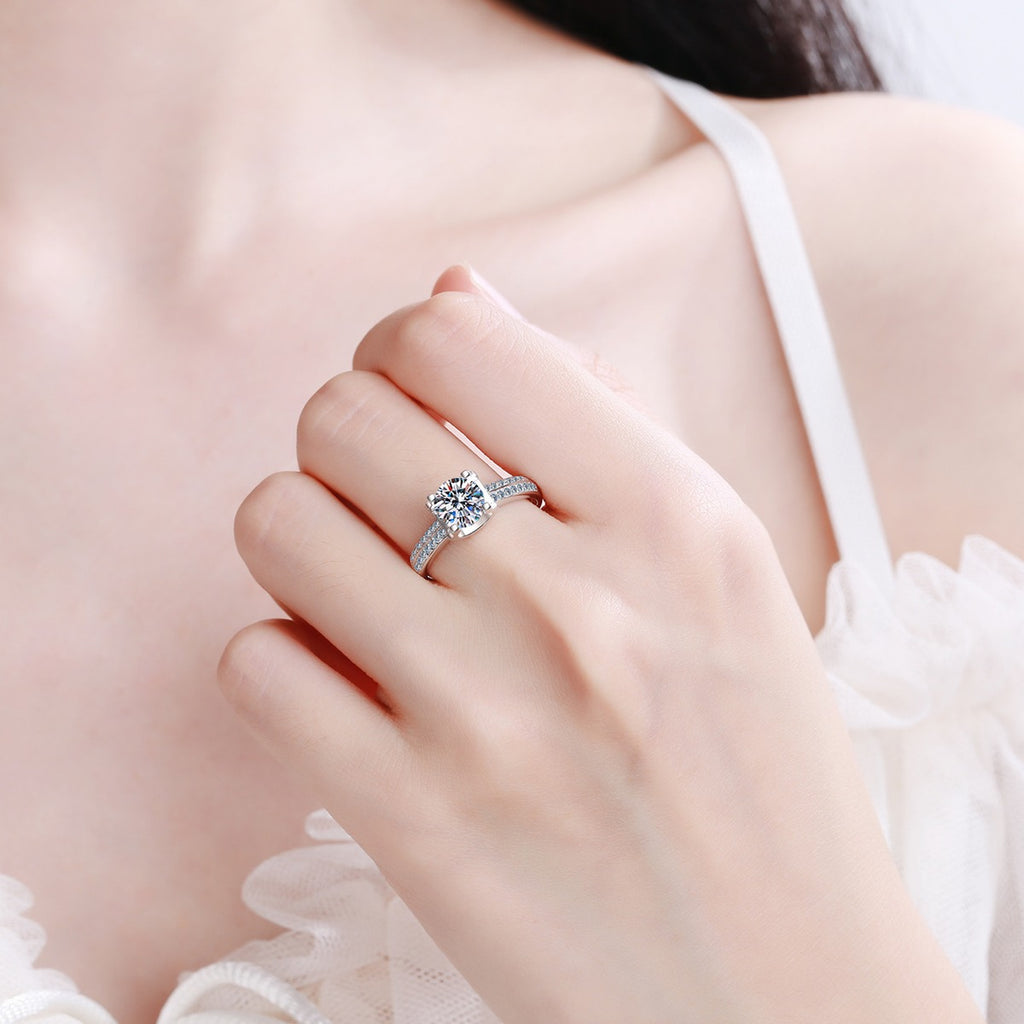 Round Moissanite Side Stone Engagement Ring with CZ worn on hand to show scale, band width, and ring profile