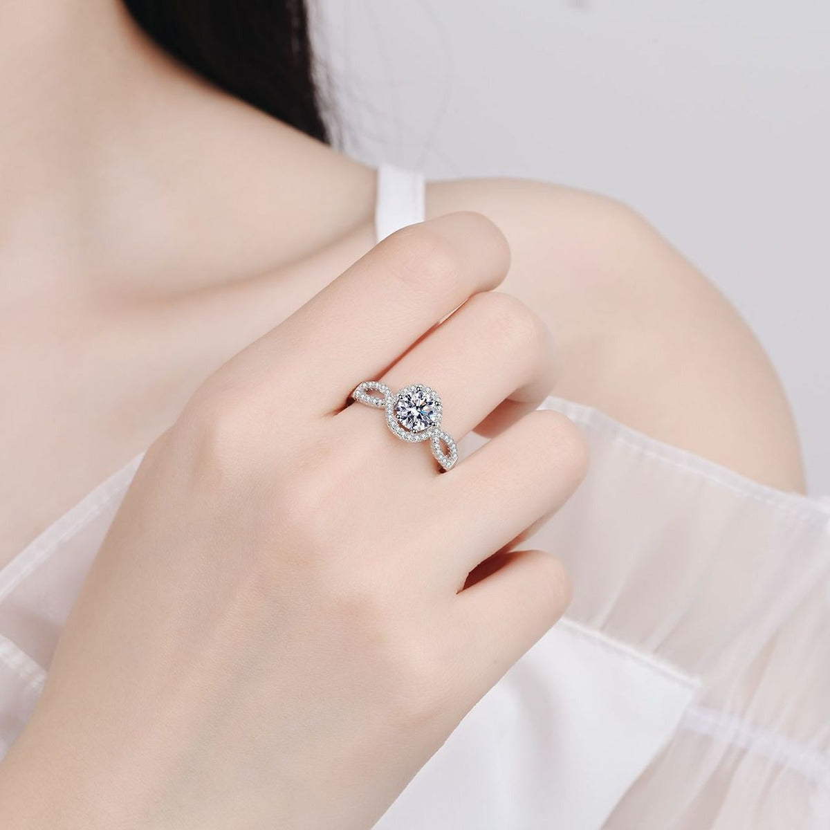 Round Halo Moissanite Twist Ring with CZ worn on hand to show scale, band width, and ring profile