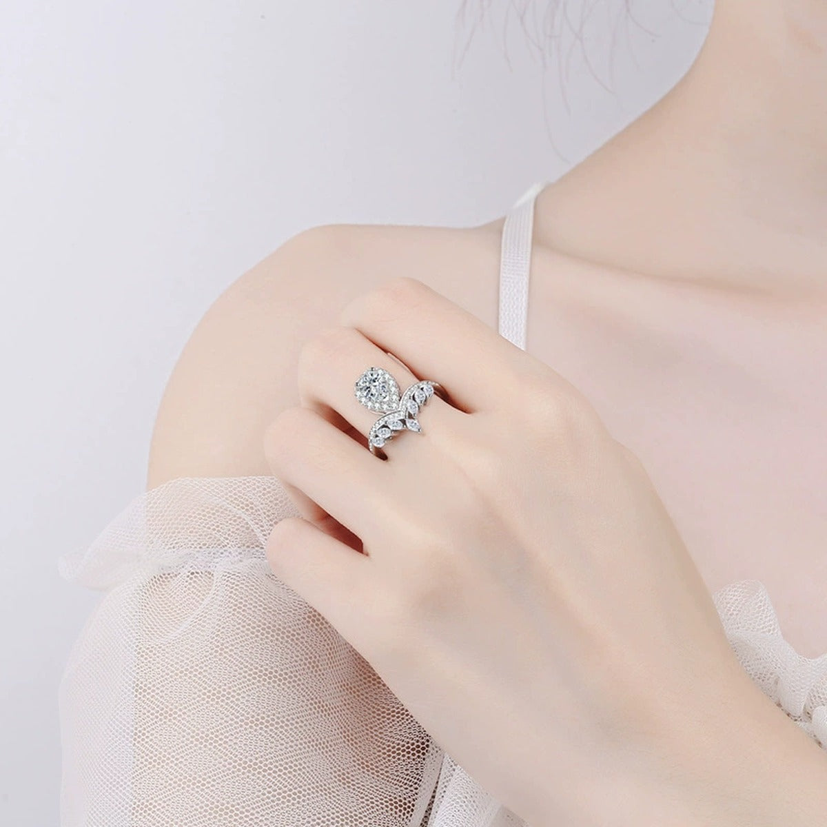 Pear Cut Moissanite Side Stone Engagement Ring with CZ worn on hand to show scale, band width, and ring profile