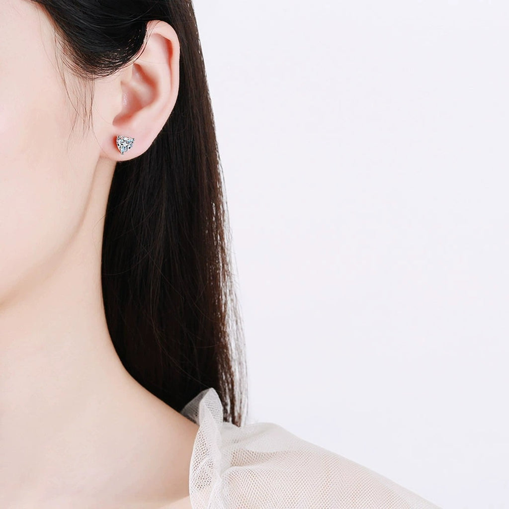 Heart Cut Moissanite Stud Earrings in Rhodium-Plated S925 sterling silver worn on ear by model showing scale, placement, and stud earrings styling