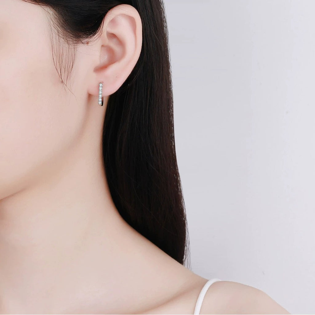 Pave Moissanite Huggie Hoop Earrings in Rhodium-Plated S925 sterling silver worn on ear by model showing scale, placement, and huggie hoop earrings styling