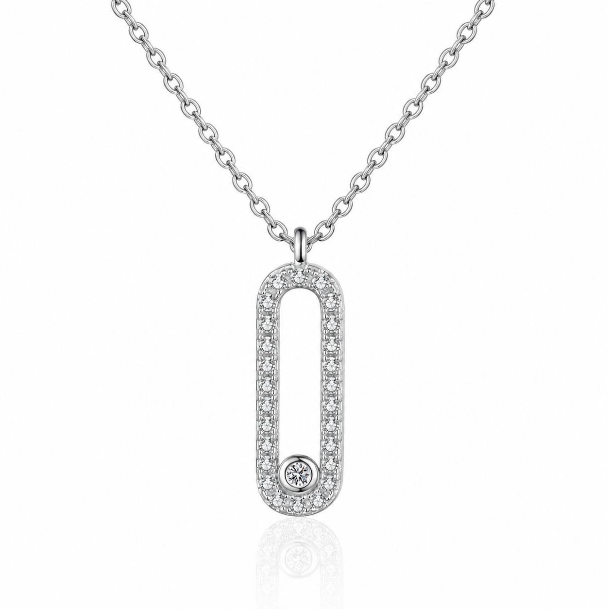 A silver-toned oval pendant necklace with a border of small clear stones and a single round stone at the bottom, shown on a white background with a faint reflection.