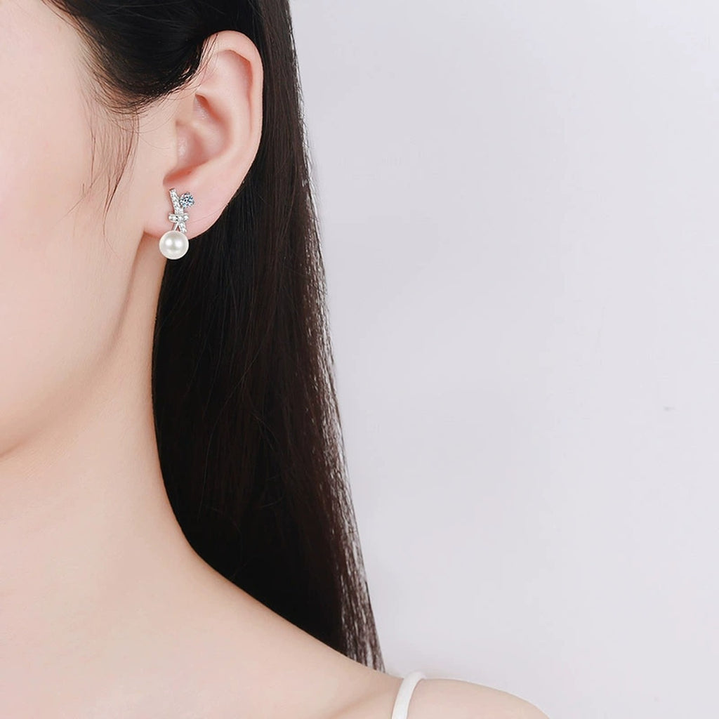 Bow Pearl Moissanite Stud Drop Earrings in Rhodium-Plated S925 sterling silver worn on ear by model showing scale, placement, and stud earrings styling