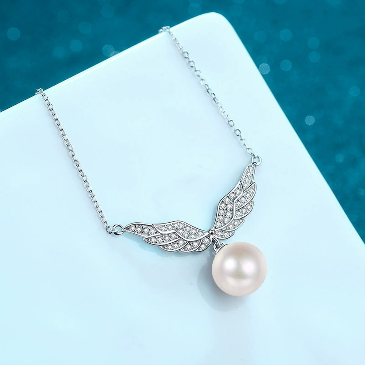 Angel Wing Moissanite Pearl Pendant Necklace in Rhodium-Plated S925 sterling silver blue display scene showing chain and stone layout