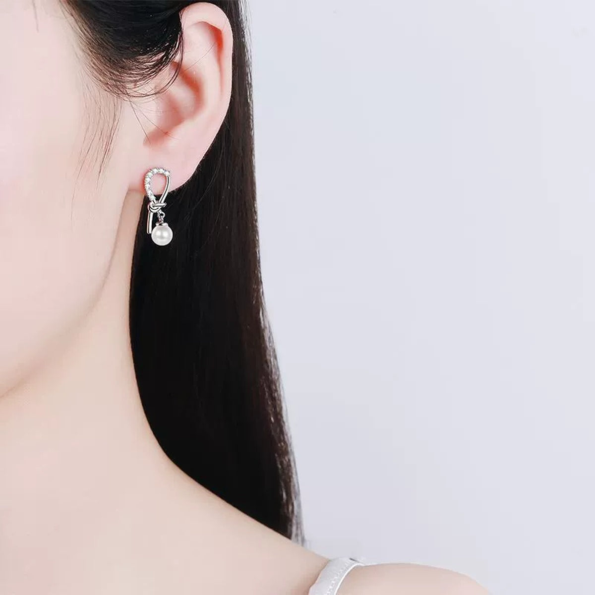 Ribbon Bow Pearl Moissanite Stud Dangle Earrings in Rhodium-Plated S925 sterling silver worn on ear by model showing scale, placement, and stud dangle earrings styling