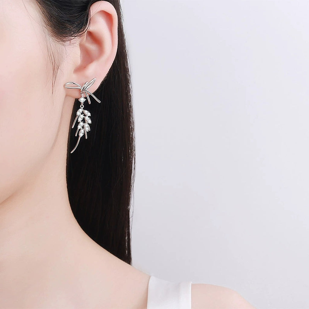 Bow Moissanite Stud Dangle Earrings in Rhodium-Plated S925 sterling silver worn on ear by model showing scale, placement, and stud dangle earrings styling
