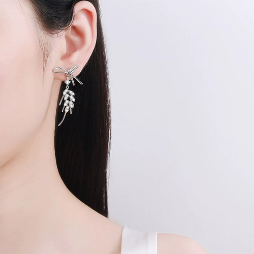 Bow Moissanite Stud Dangle Earrings in Rhodium-Plated S925 sterling silver worn on ear by model showing scale, placement, and stud dangle earrings styling