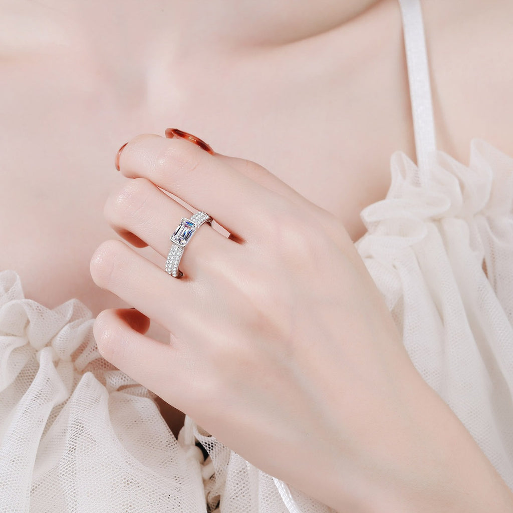 Emerald and Radiant Cut Moissanite Side Stone Engagement Ring with CZ worn on hand to show scale, band width, and ring profile